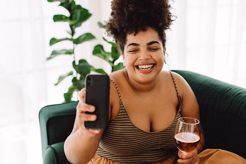 Woman taking selfie with glass of wine at home