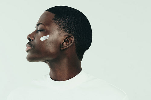 Black man taking care of his melanin skin with a beauty cream