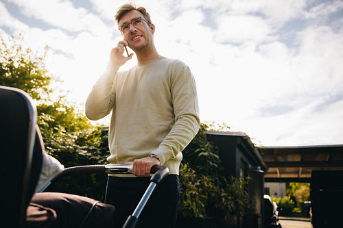 Multitasking father pushing baby stroller