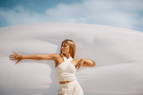 Woman in a white outfit posing outdoors on a breezy sunny day