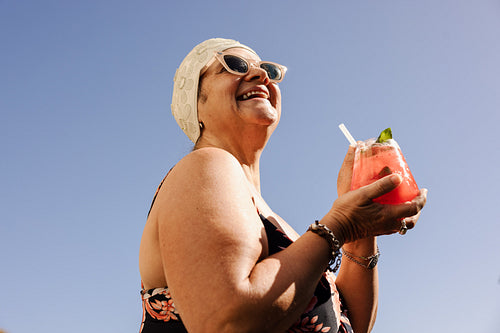 Joyful senior woman enjoying a tiki cocktail in the summer
