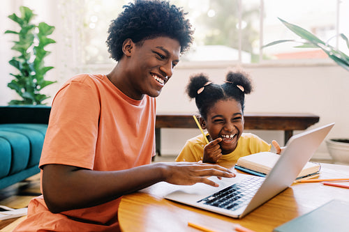 Siblings helping each other with online schoolwork at home