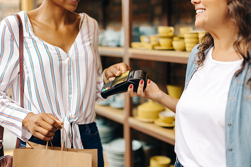 Happy ceramic shop owner receiving a credit card payment from a customer