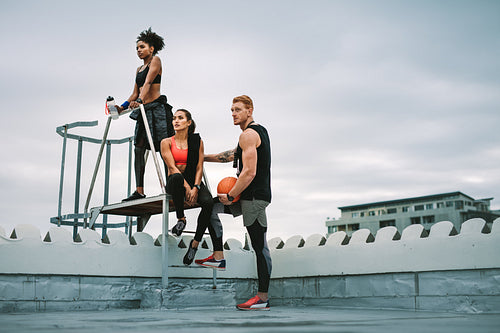 Fitness people taking a break from workout standing on rooftop