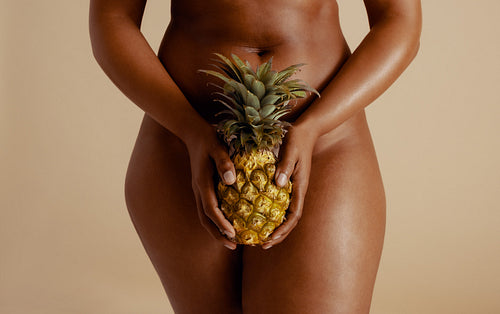 Empowering female wellness: Sensual woman holding a pineapple in a studio