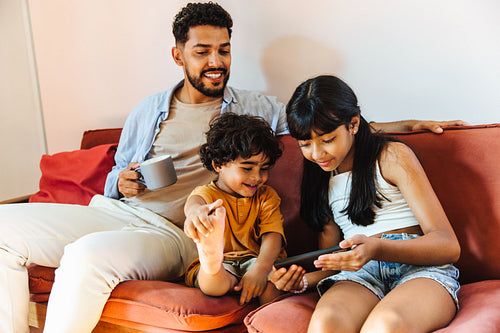 Latino family spending quality time on a couch with a digital device