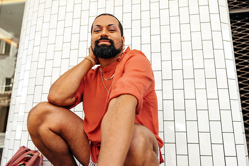 Carefree drag queen squatting against a white background