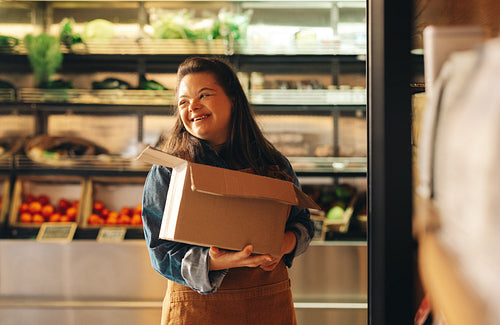 Smiling woman with Down syndrome working in a grocery store