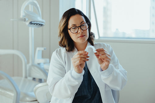 Examining the retainer, the dentist shows careful treatment planning in the clinic