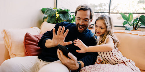 Father and girl share a joyful moment while on a video call