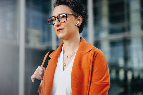 Mature businesswoman listening to music on her earphones while walking to work