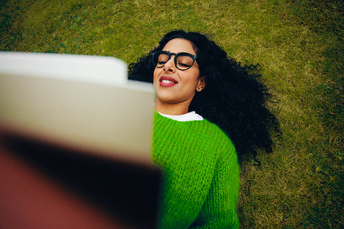 Woman reading book on grass outdoors in a quiet study moment