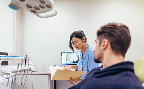 Dentist examining the reports of patient in clinic