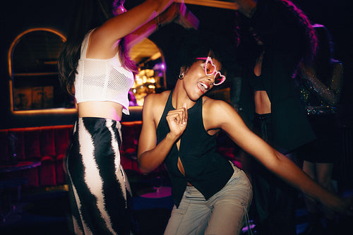 Vibrant young adults dancing with joy in a lively modern nightclub setting