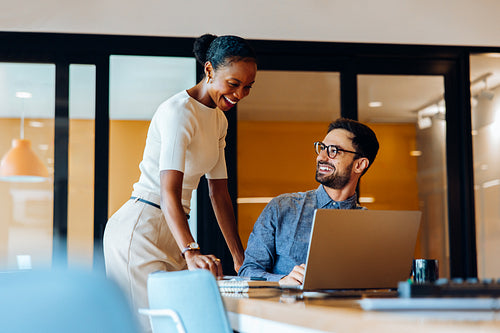Colleagues interacting and smiling during a casual discussion in an office environment