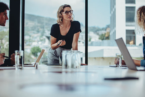 Businesswoman discussing work with coworkers in meeting