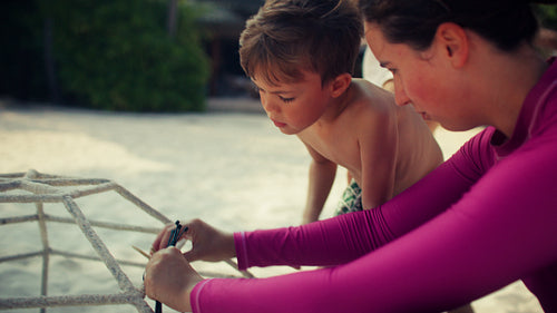 Family and volunteers engaging in coral conservation on a tropical beach