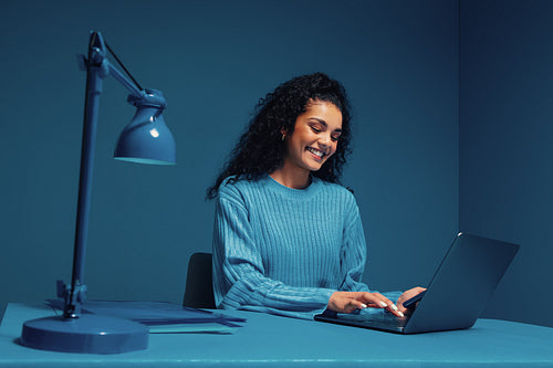 Monochromatic studio shot of female entrepreneur working on laptop