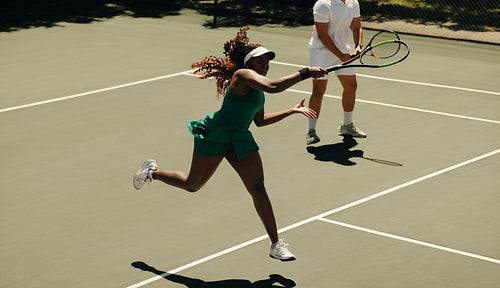 Mixed doubles tennis match with players jumping to hit the ball