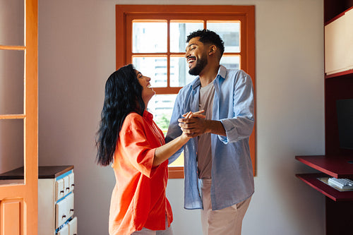 Happy couple smiling and dancing together in a cozy living space