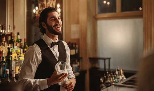 Smiling bartender cleaning glasses