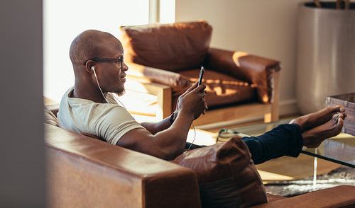 Man relaxing at home listening to music