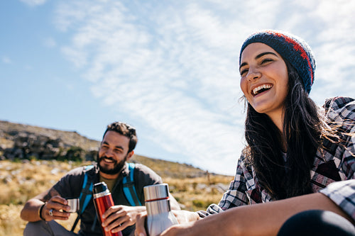 Cheerful hikers having rest on field