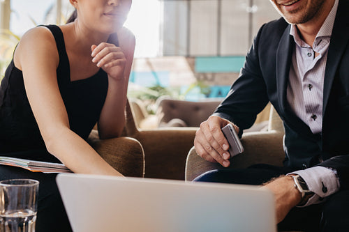 Businesspeople sitting together working on laptop