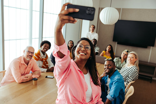 Diverse team of colleagues taking a cheerful group selfie during a team meeting