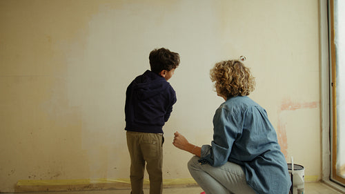 Mother and son painting a wall white during home renovation