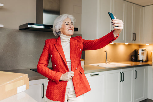 Fashionable senior woman showing off her new jacket on a video c