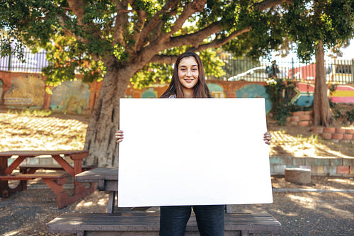 Young female activist displaying a blank banner outdoors