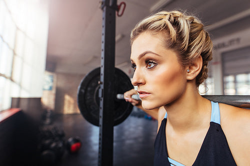 Woman working out at the gym using weight bar.