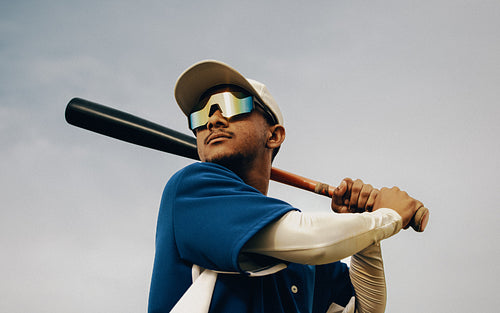 Professional baseball player in action wearing polarized sunglasses during game day holding a bat