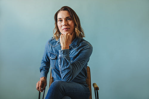 Successful female entrepreneur in denim, showing confidence while sitting on chair