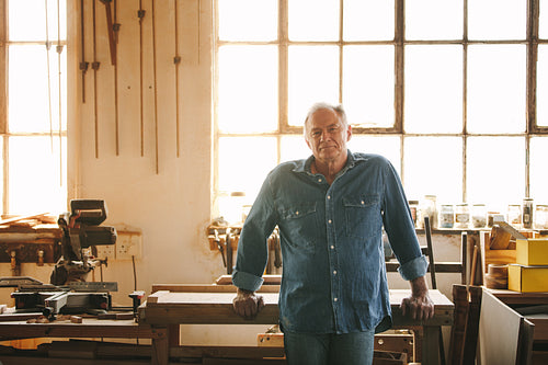 Senior man standing by a table in his carpentry workshop