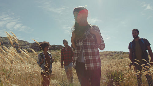 Young friends walking through grass fields in countryside