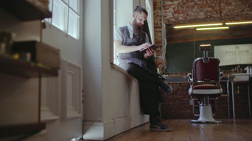 Barber organizing his business using digital tablet