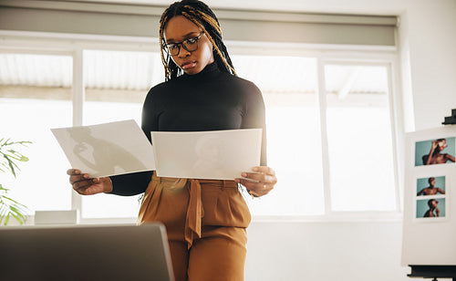 Young woman looking at two photographs in her office