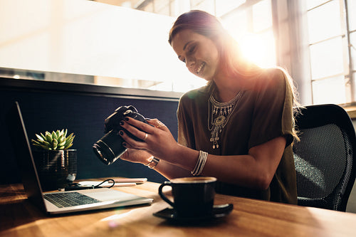 Young female photographer watching her camera while editing her vlog on computer.