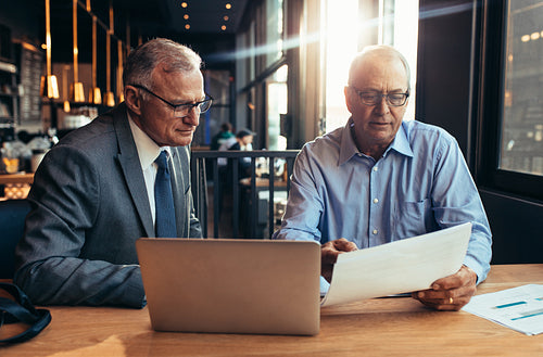Senior businessmen at cafe discussing over a report