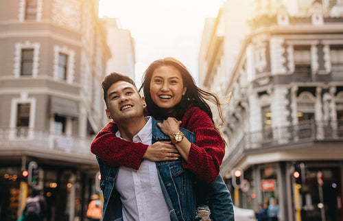 Asian couple piggybacking on city street