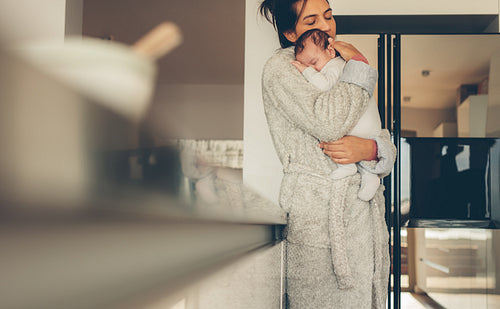 Caring mother with newborn baby boy in kitchen