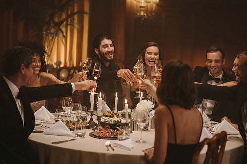 Multi-ethnic people celebrating with drinks at dinner party