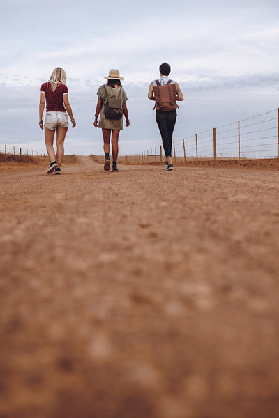 Female friends walking on country road after their car breakdown