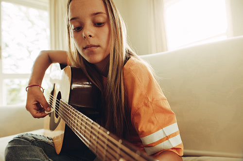 Girl practicing guitar at home