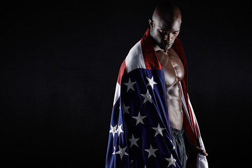 Muscular man wrapped in the American flag with copy space