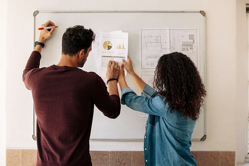 Business partners discussing work on a whiteboard in office