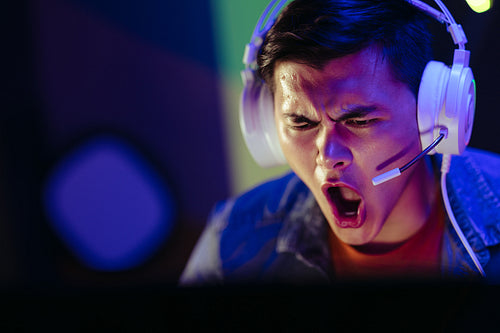 Young man looking at his gaming computer with an expression of shock