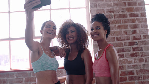 Cheerful female friends taking self portrait at gym